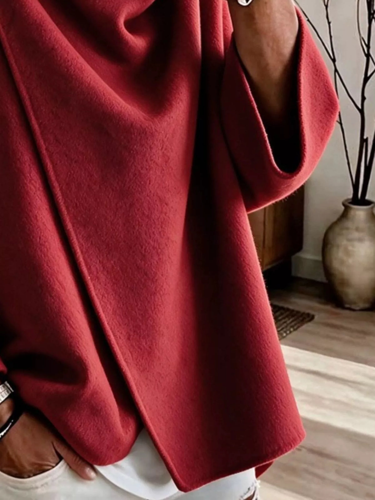Red asymmetric cowl-neck cape, close-up of the draped neckline and button detail