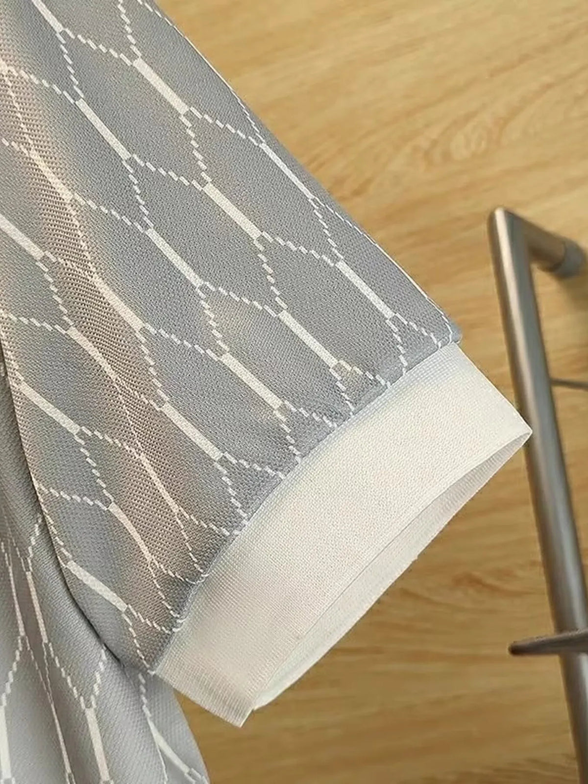 Close view of the Grey polo's diamond-pattern fabric and light ribbed sleeve edge.