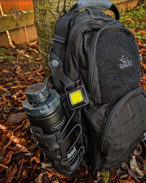 Powertac SOL light clipped to a backpack strap outdoors.