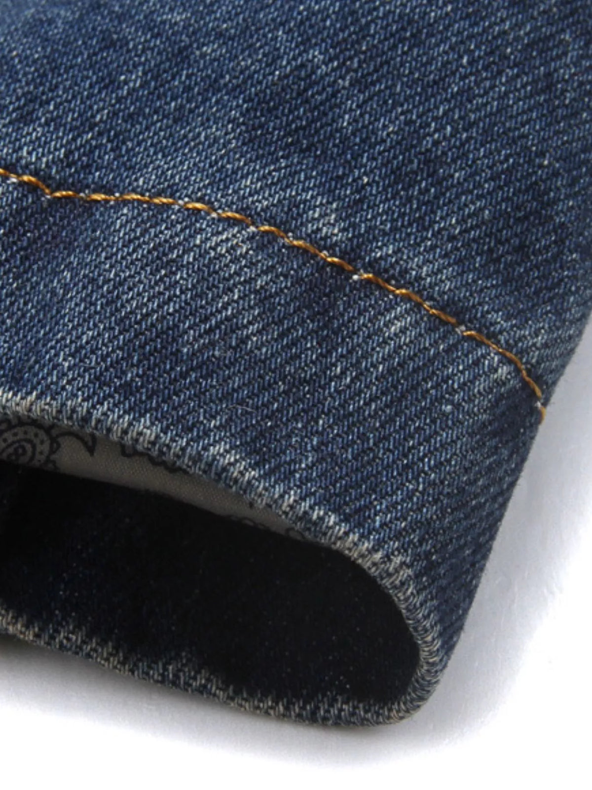 Close-up of the blazer's sleeve hem showing the denim weave and contrast stitching.