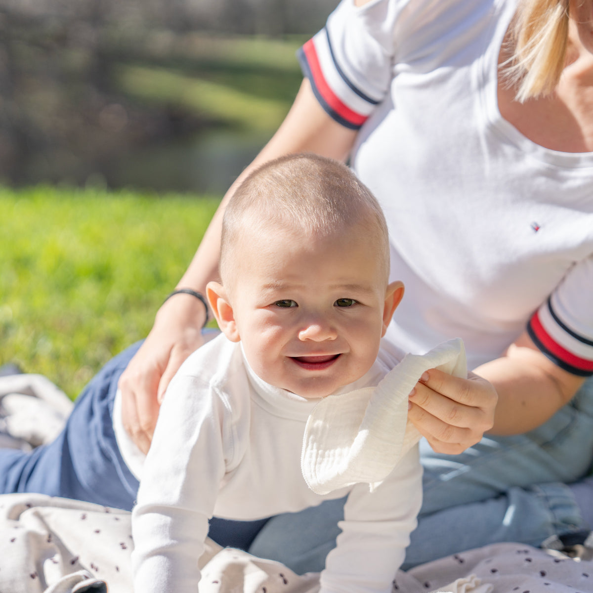 Parent holding a baby outdoors and holding a reusable cotton wipe