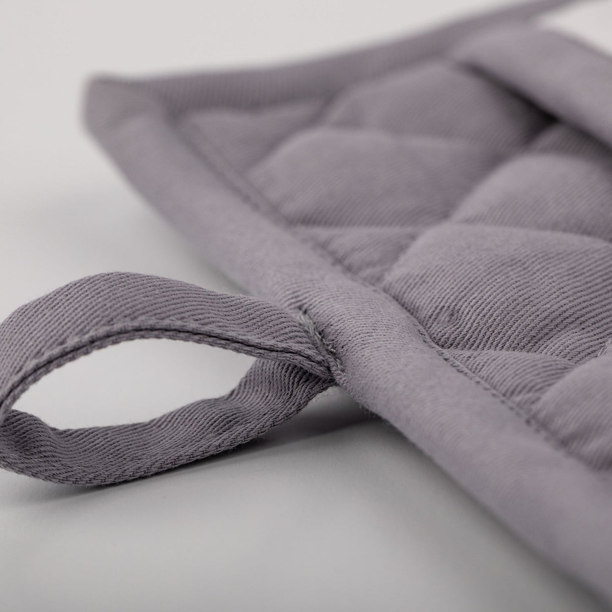 Close-up of the gray quilted fabric and hanging loop.