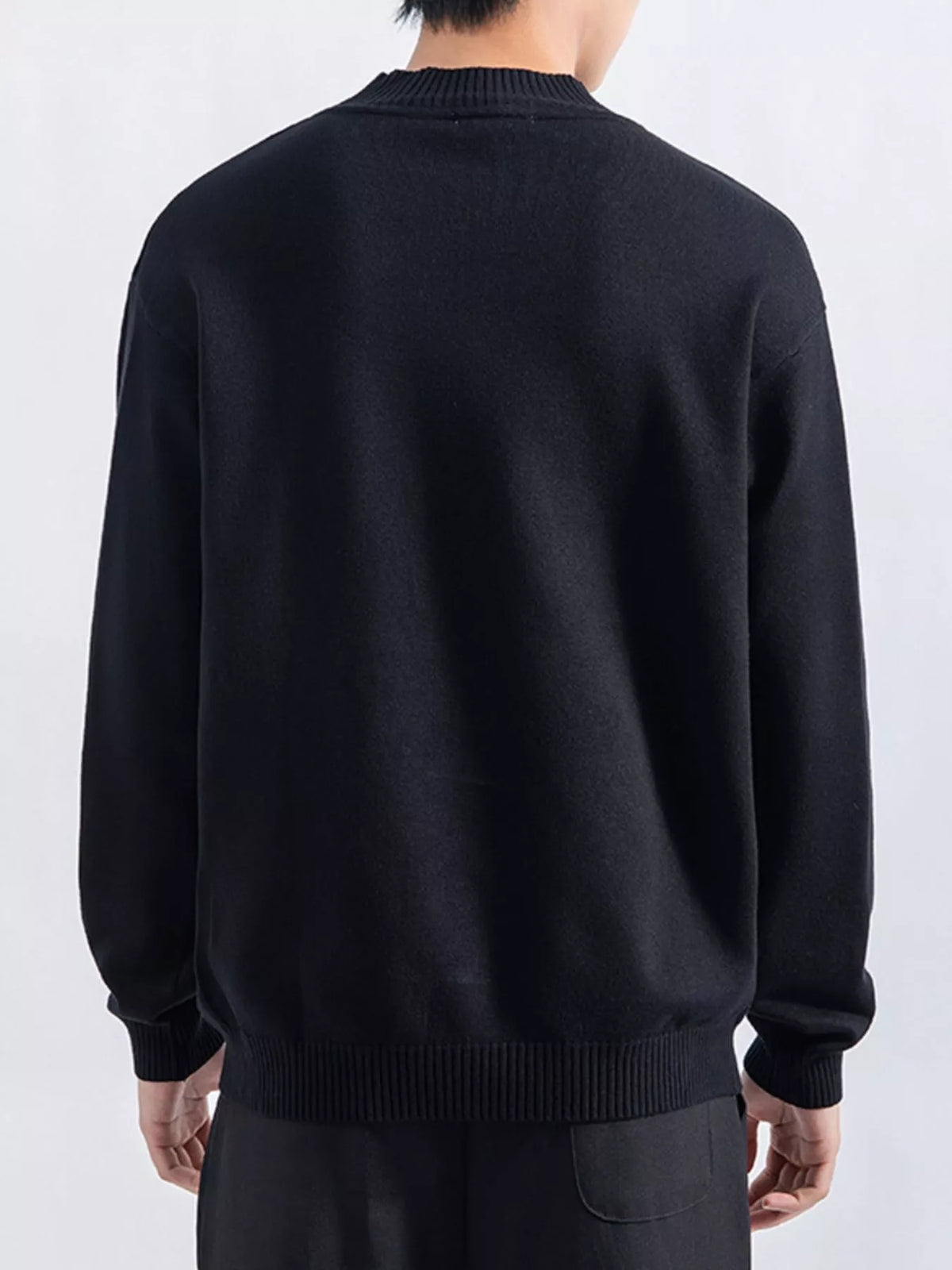 Men's Black minimalist mock-neck sweater, back view. Trousers are styling items and are not included.