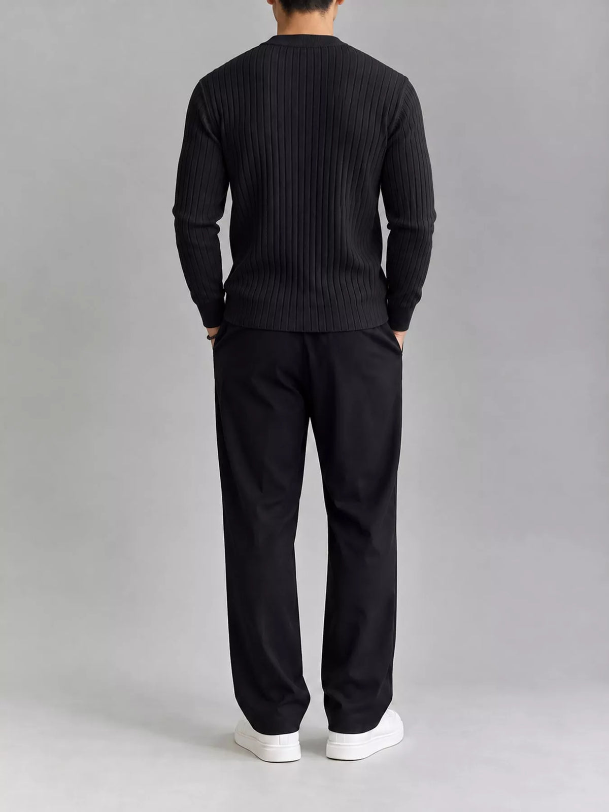 Black ribbed knit top, modelled rear view. Trousers and shoes are not included.