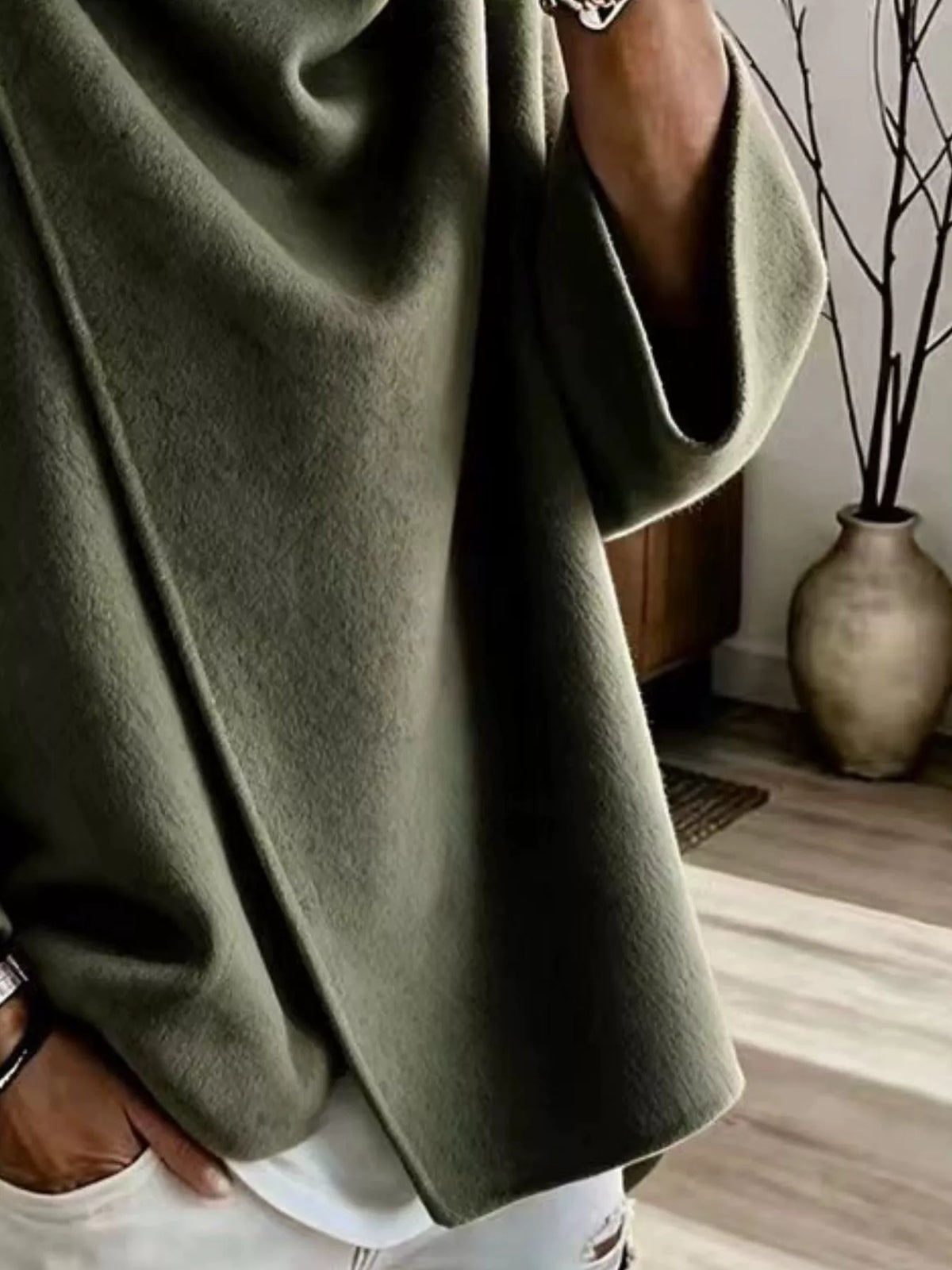 Green asymmetric cowl-neck cape, close-up of the draped neckline and button detail