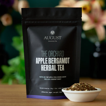 August Uncommon Tea The Orchard 15-cup herbal tea bag beside brewed tea