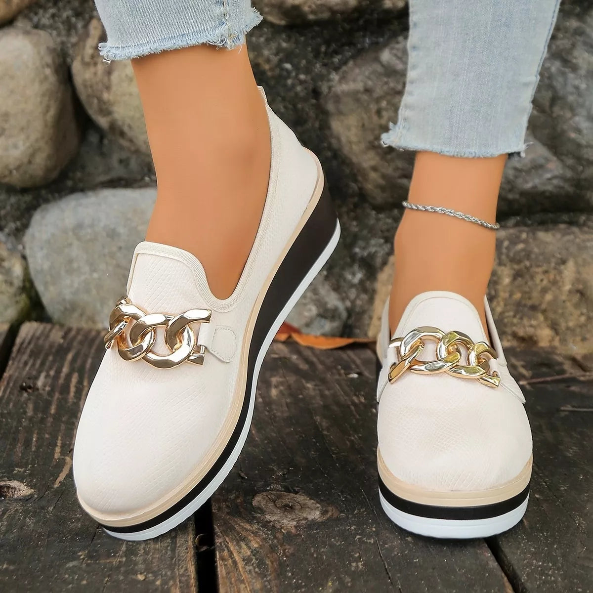 Front view of beige loafers showing rounded toes and chain-style trim.