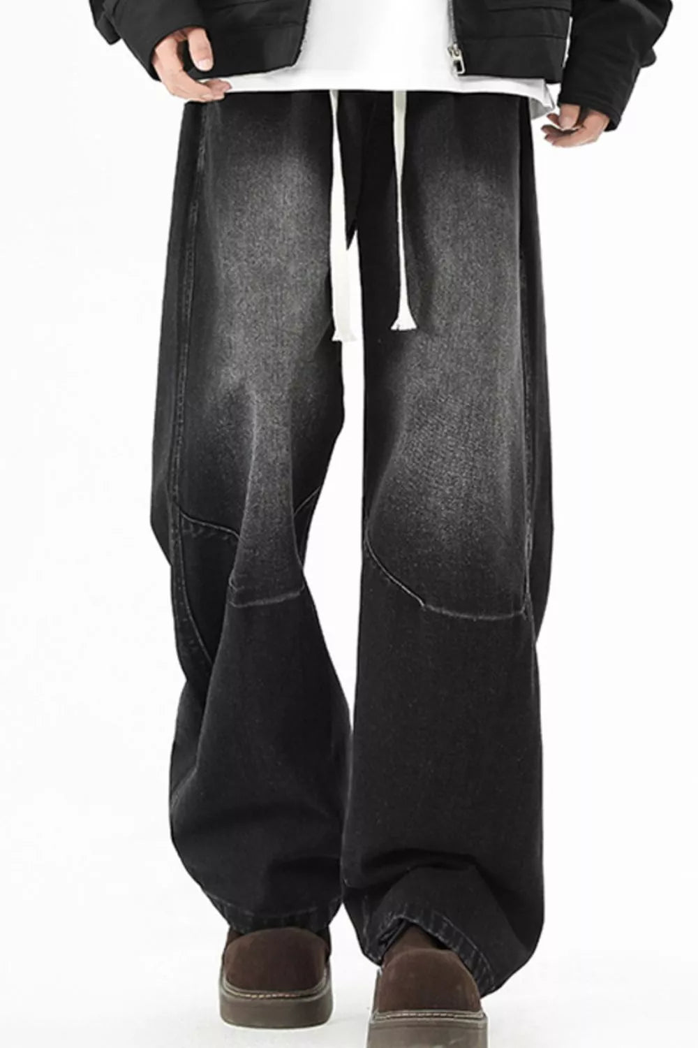 Black men's wide-leg drawstring jeans, front view showing the curved panel seams.