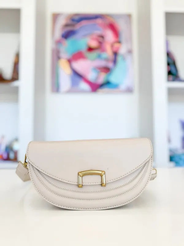 Beige crescent crossbody bag with gold-tone buckle detail, front view