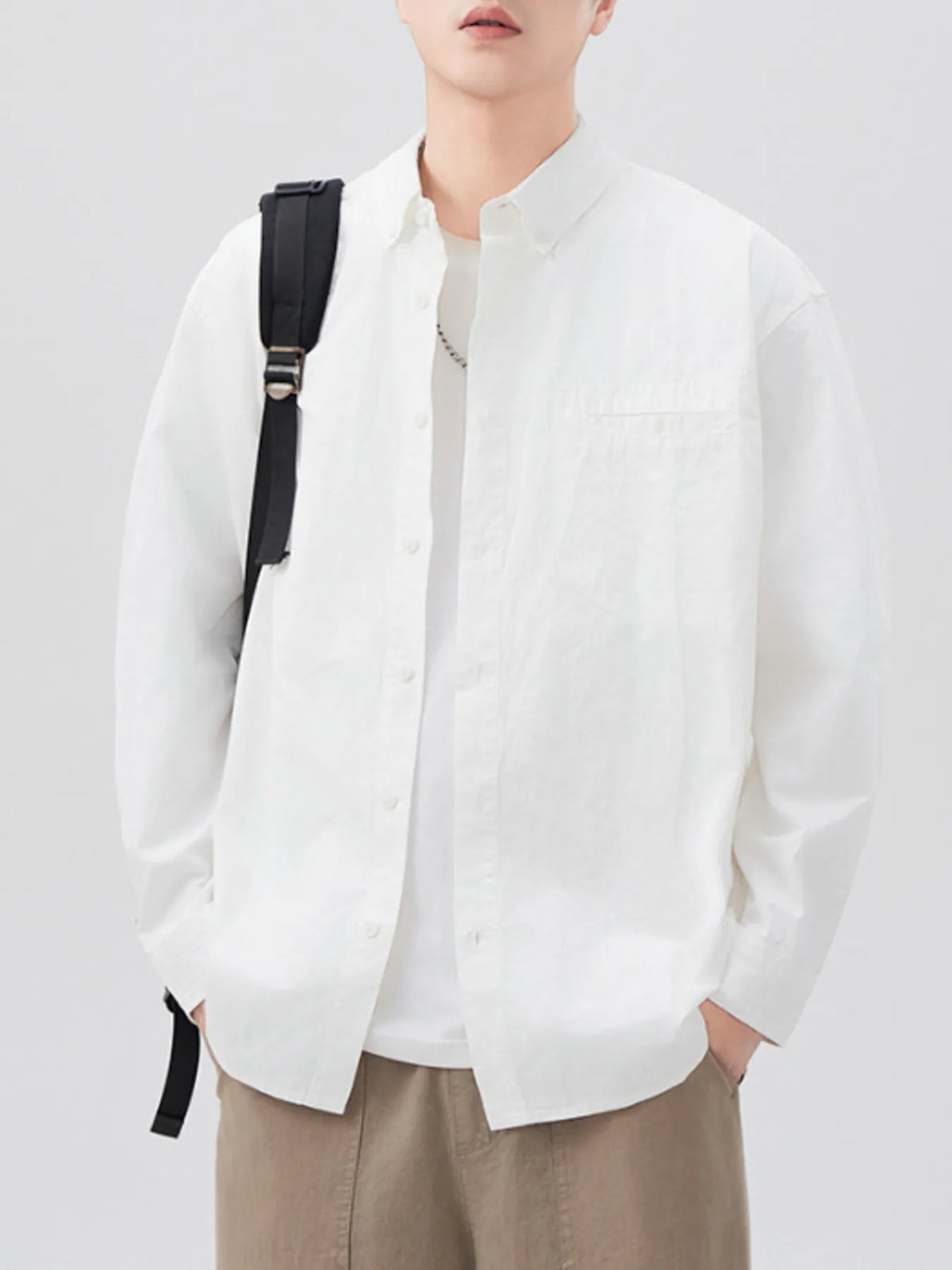 White long-sleeve shirt open over a white T-shirt, front view with bag strap