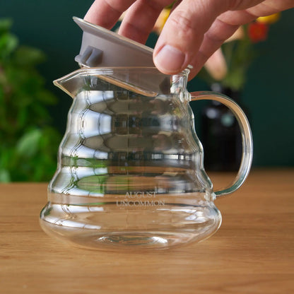 Hand placing a separate infuser into the August glass teapot; infuser not included