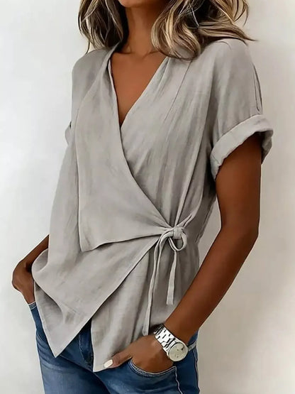 Gray wrap top on a model in an angled front view, showing the side bow and overlapping front panels.