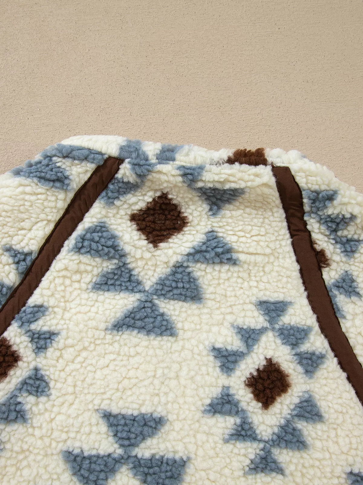Close-up of geometric motifs and brown seam trim on the sweatshirt.