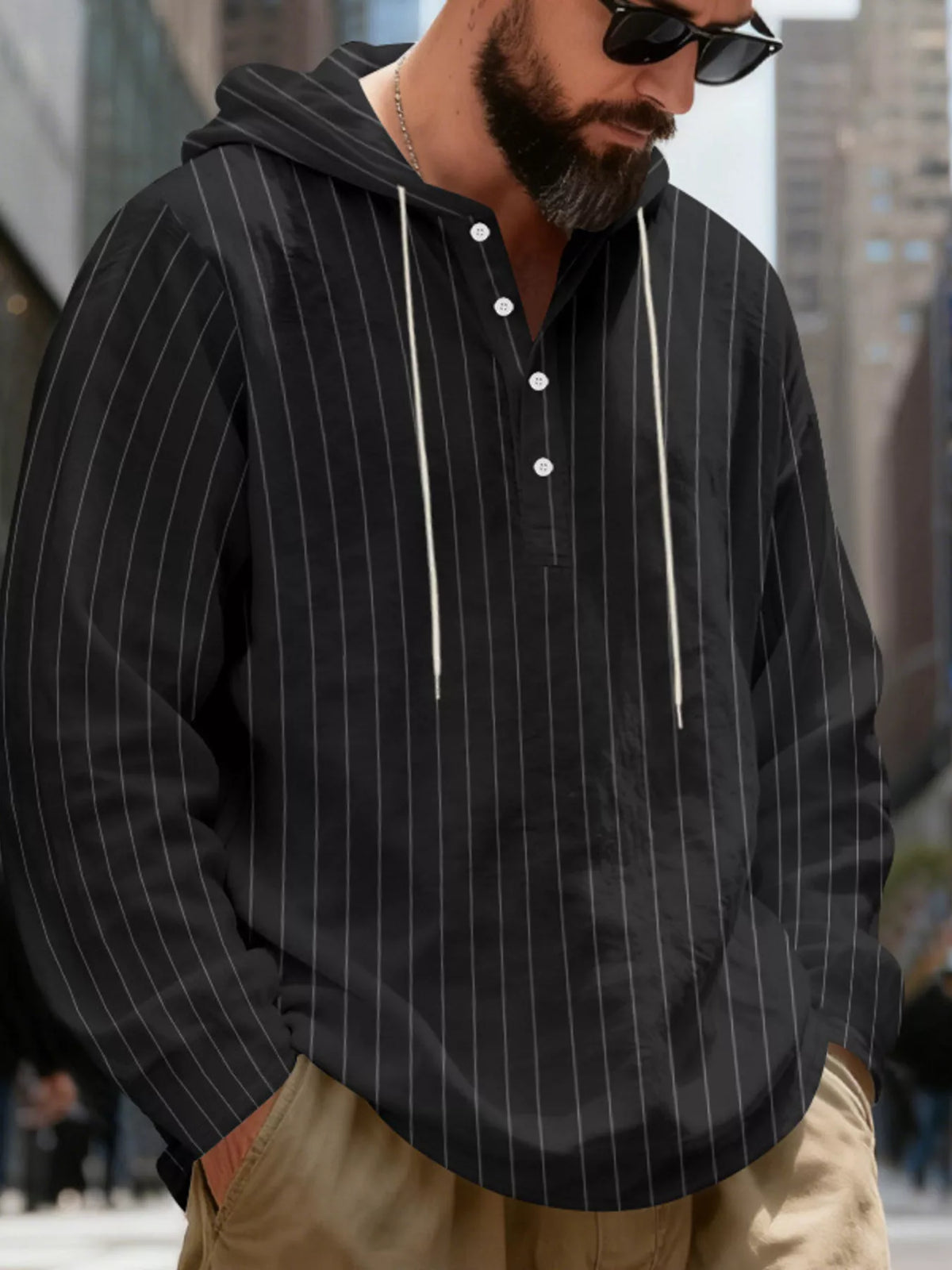 Men's striped Henley hoodie in Black — angled front view showing the hood and buttoned neckline; trousers and accessories are styling only.