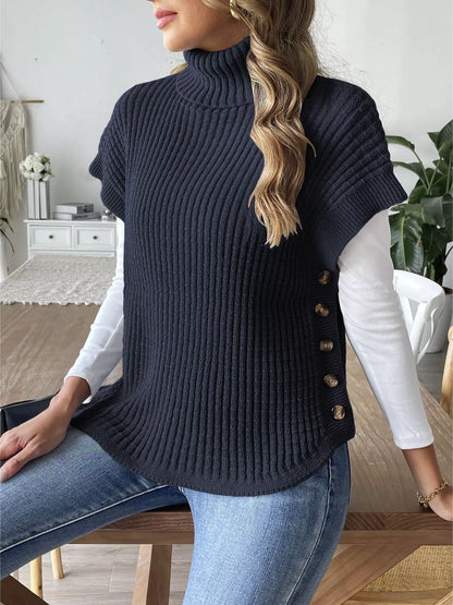 Seated side-front view of the Navy Blue ribbed turtleneck sweater vest over a separate white top.