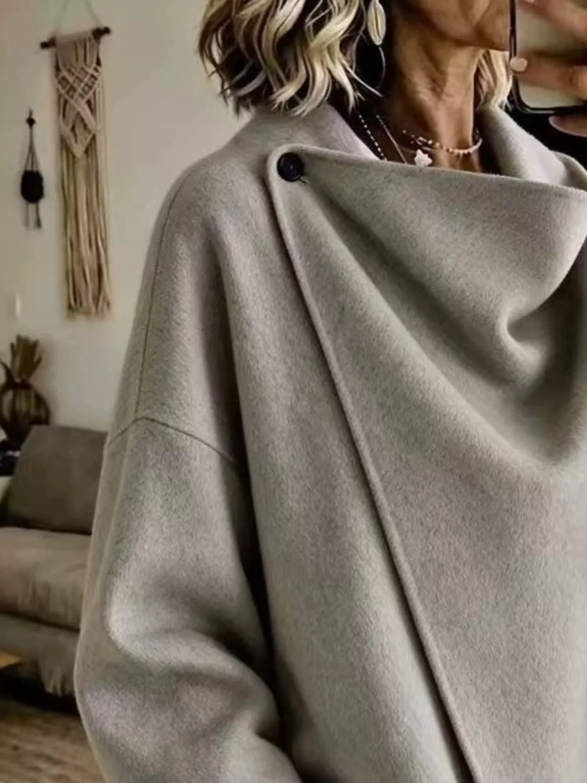 Gray asymmetric cowl-neck cape, close-up of the draped neckline and button detail