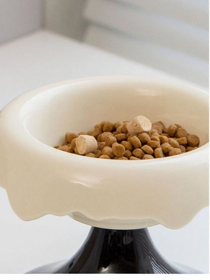 Close-up of a white bowl with black pedestal and pet food.