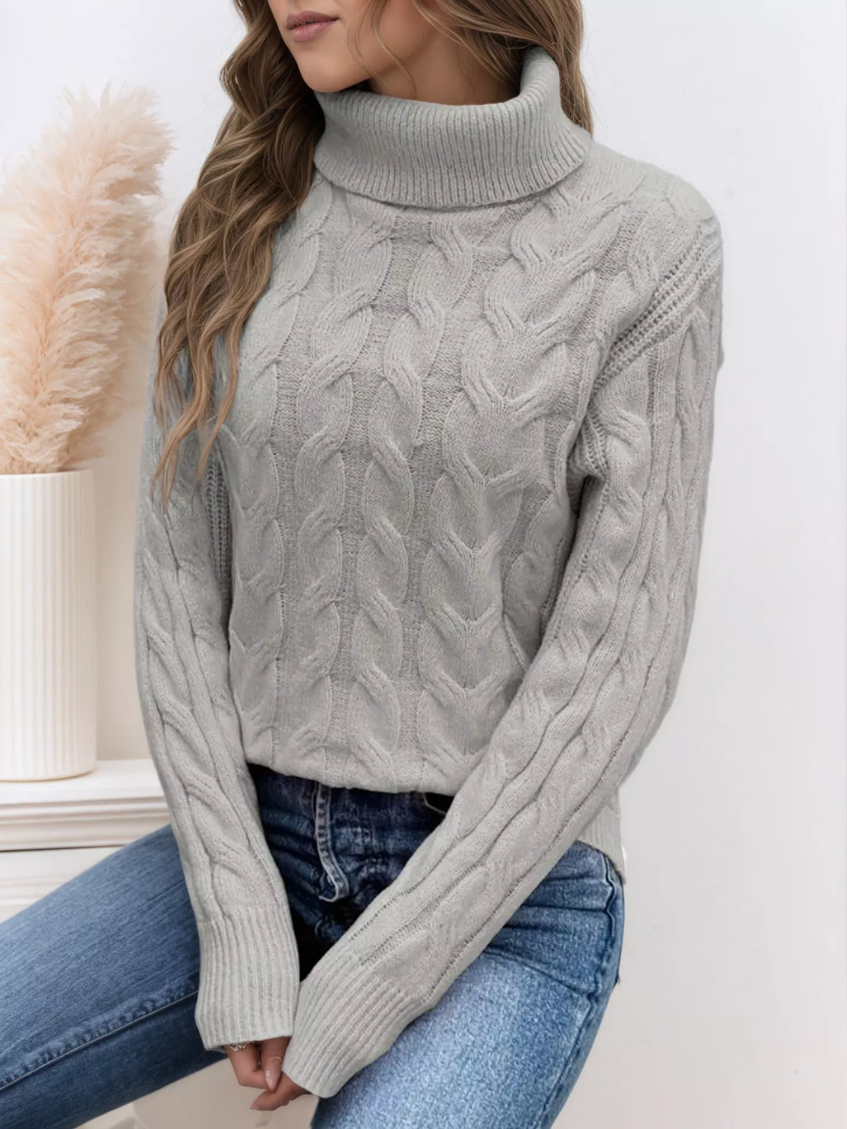 Cable-knit turtleneck sweater with long sleeves.