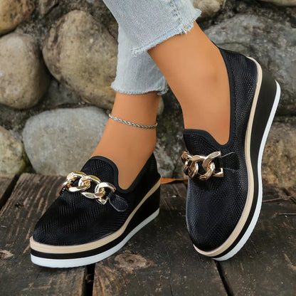 Black round-toe wedge loafers worn, with contrasting light trim above the sole.