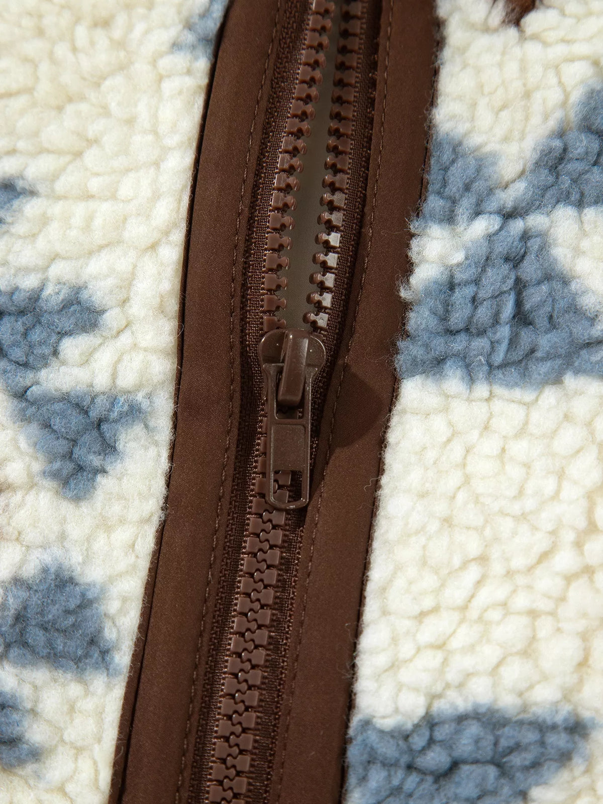 Close-up of the brown zipper and surrounding geometric sherpa fabric.