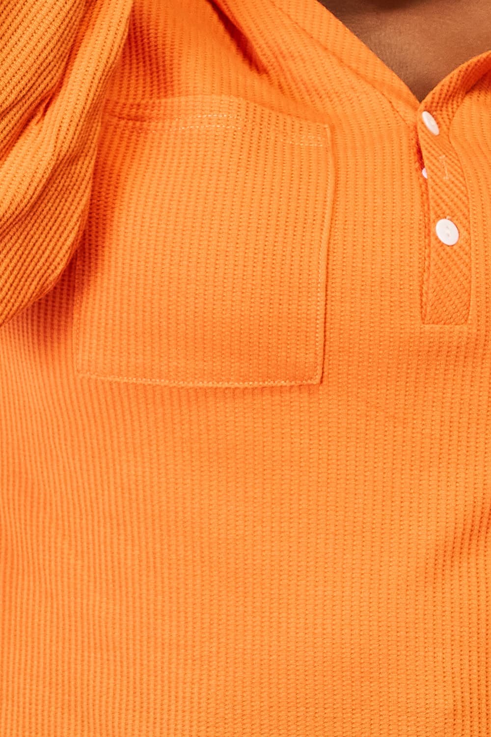 Close-up of the Orange waffle-knit fabric and buttoned neckline