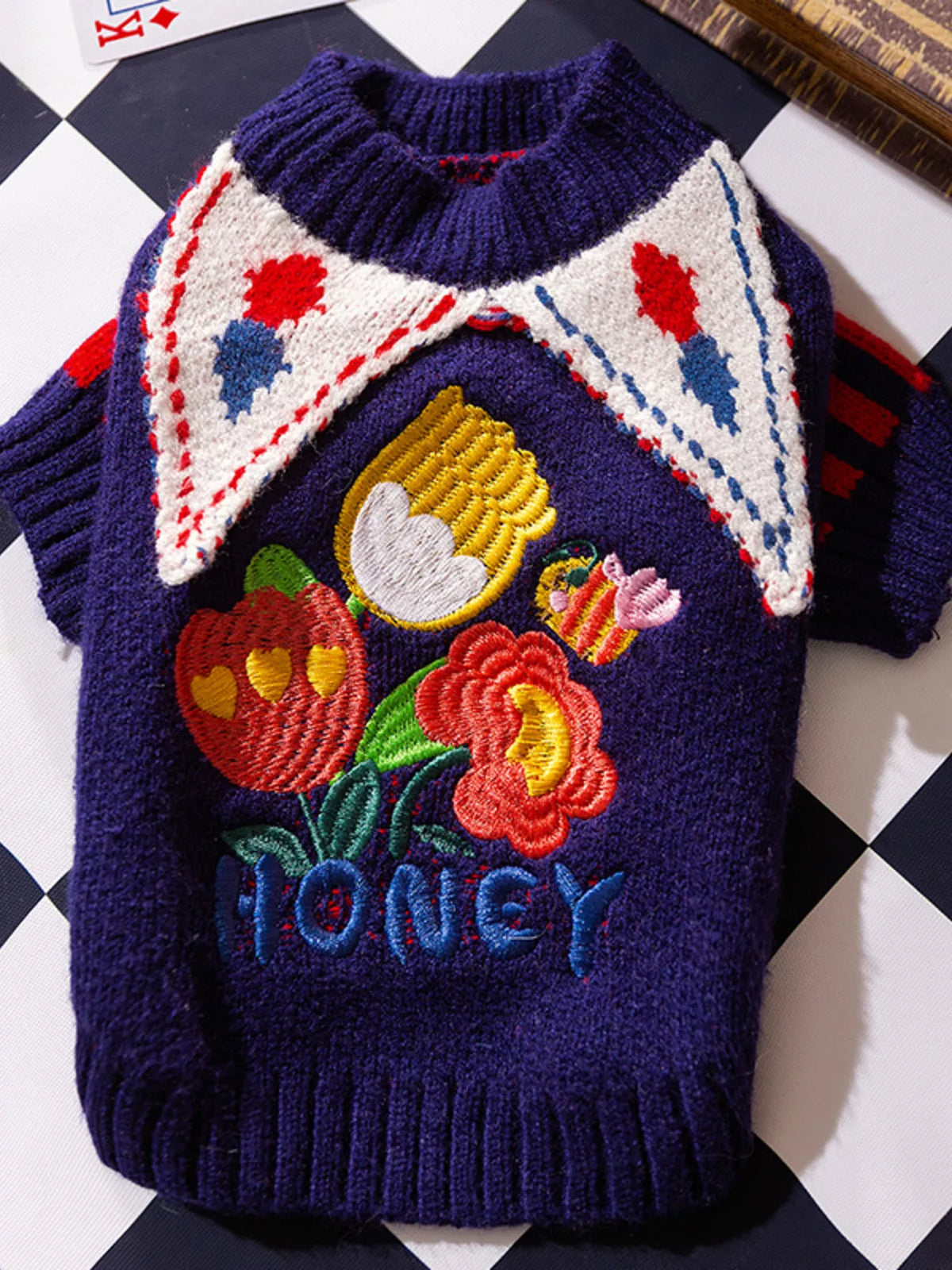 Navy pet sweater with colorful fruit appliques and decorative lettering, shown flat.