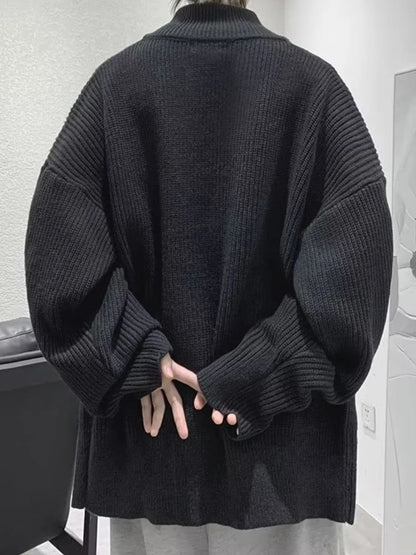 Back view of the black oversized ribbed cardigan, showing its dropped shoulders and long sleeves.