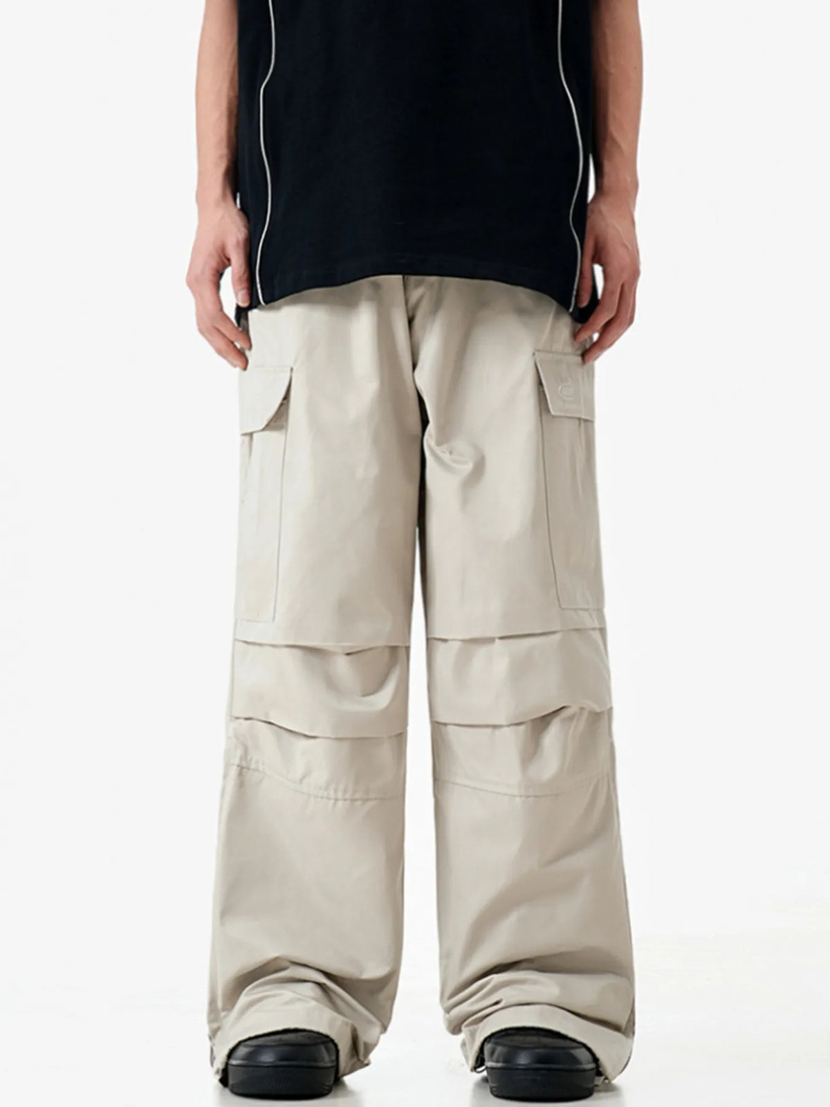 Front view of light apricot cargo trousers on a model, showing flap pockets and relaxed full-length legs.