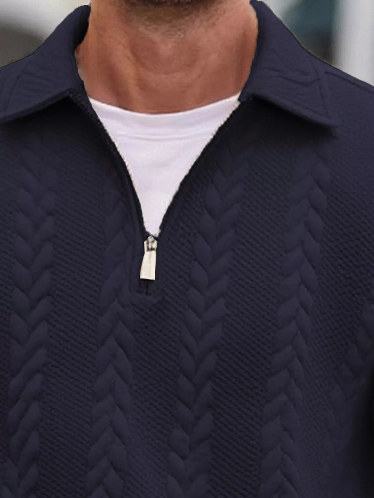 Close view of the navy pullover's collar, short zipper and cable-textured knit.