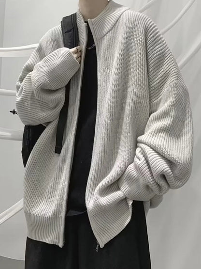 Gray ribbed zip-up cardigan worn open over separate dark clothing, with a styling bag.