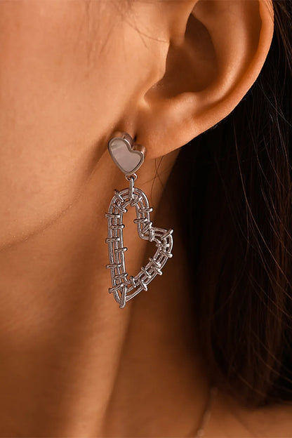 Silver-tone heart drop earring with a pale heart-shaped stud and open wrapped-wire heart pendant, shown worn.