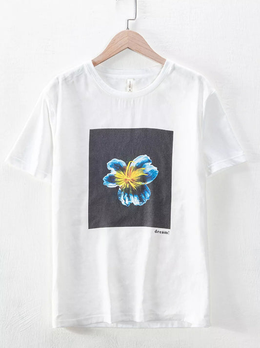 White round-neck short-sleeve T-shirt on a hanger, with a blue and yellow flower in a black rectangular front graphic and small dream! text.