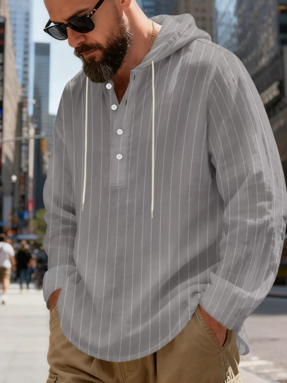 Men's striped Henley hoodie in Gray — angled front view showing the hood and buttoned neckline; trousers and accessories are styling only.