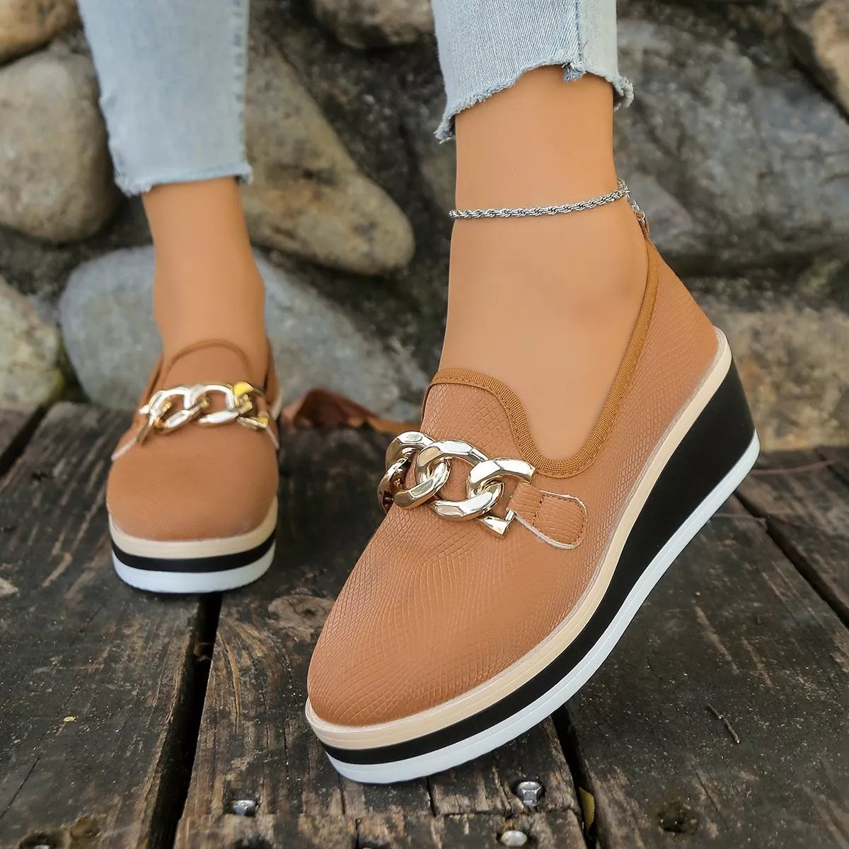 Front view of brown round-toe wedge loafers with chain-style trim.