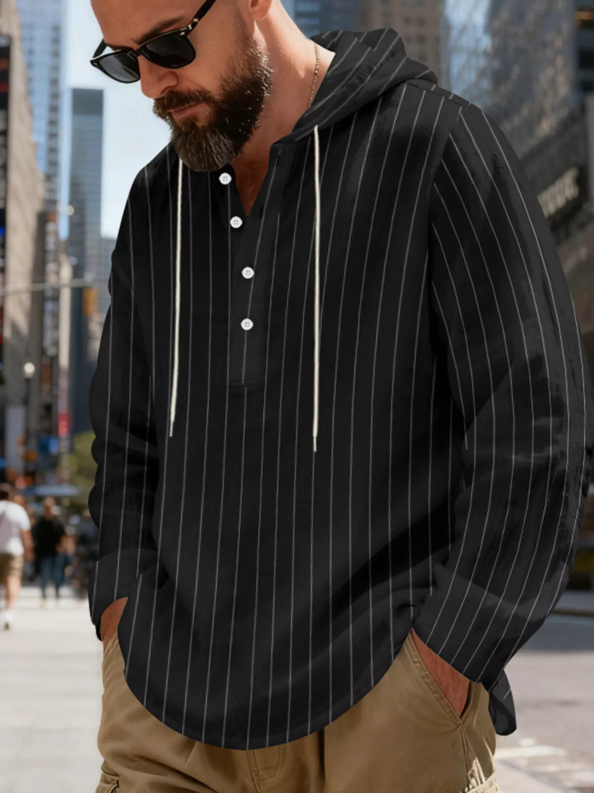 Men's striped Henley hoodie in Black — angled front view showing the hood and buttoned neckline; trousers and accessories are styling only.