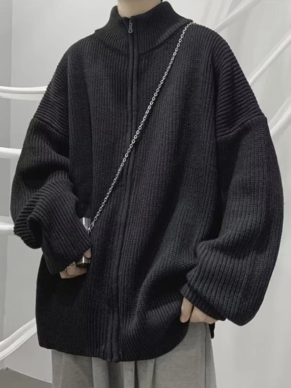 Black ribbed cardigan zipped to the stand collar; the chain and other clothing are not included.