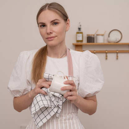 Checked cotton kitchen towel being used to dry a white cup; cup not included