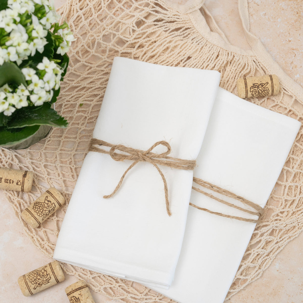 Two white flour-sack cotton napkins folded with decorative twine on a table