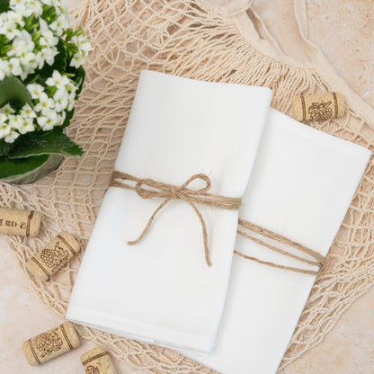 Two white flour-sack cotton napkins folded with decorative twine on a table