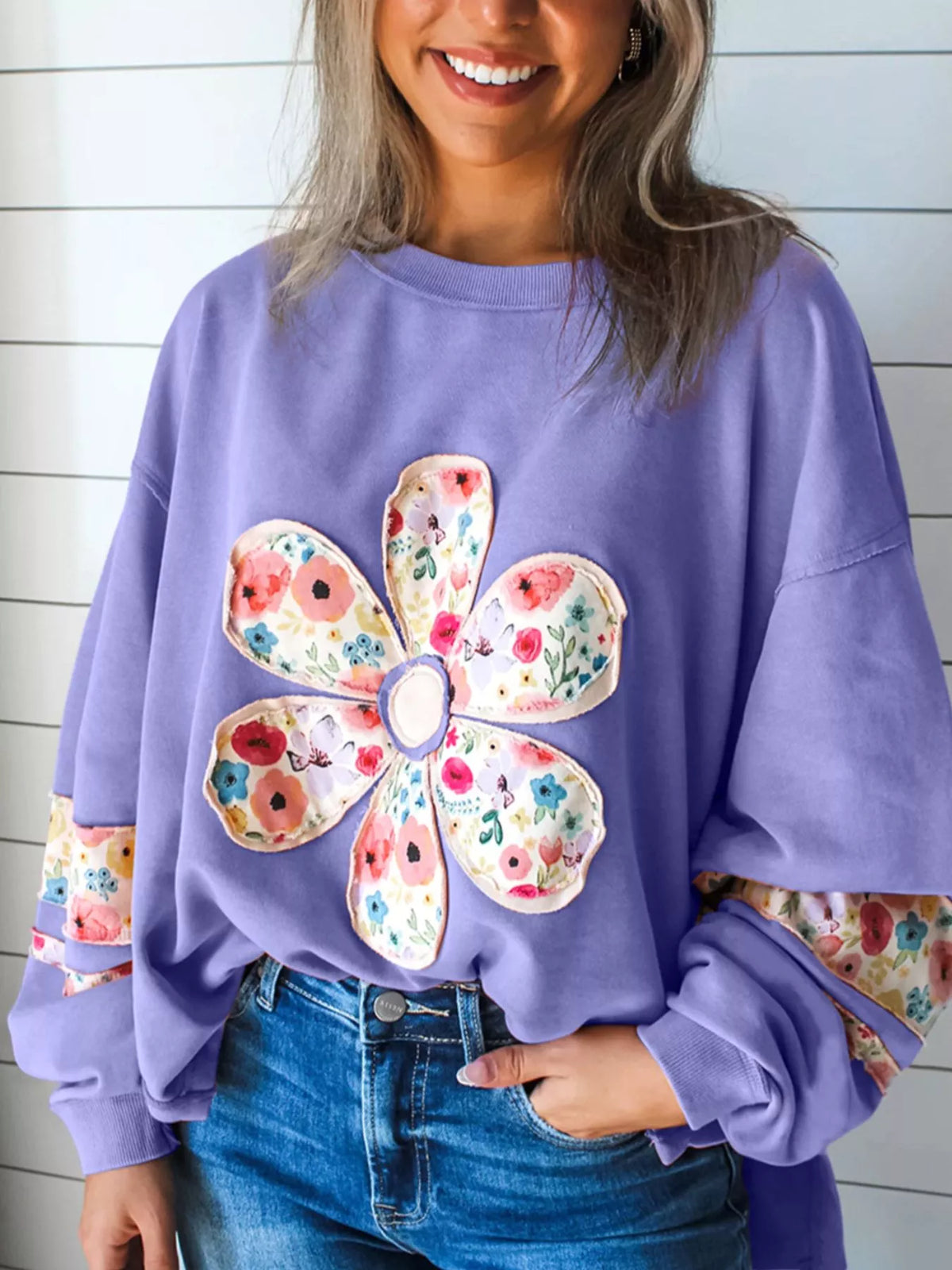 Lavender floral applique sweatshirt, front view with round neck and long sleeves. Trousers are styling only.