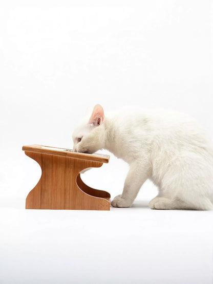 Side view of the raised wooden pet-bowl stand beside a white cat; the cat is not included.