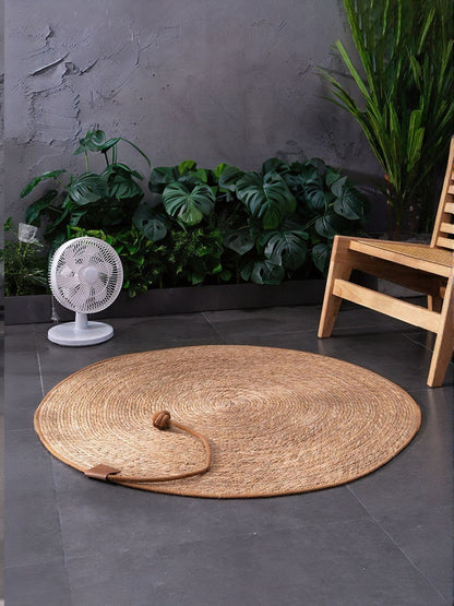 Round natural braided pet mat shown flat on the floor, with a rope-and-ball detail resting on its surface.