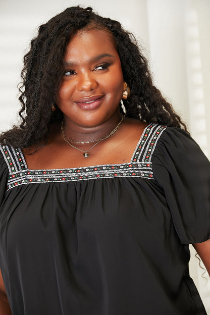 Close-up of the black Honey blouse neckline on a second model.