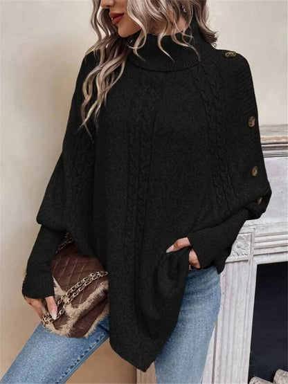 Black cable-knit turtleneck cape sweater. Front three-quarter detail, model in blue jeans. Styling accessories are not included.