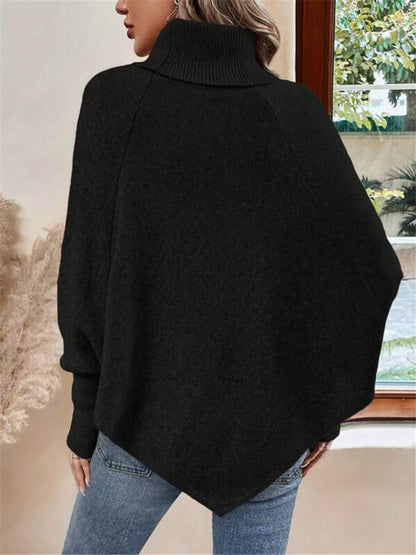 Black cable-knit turtleneck cape sweater. Rear view, model in blue jeans. Styling accessories are not included.