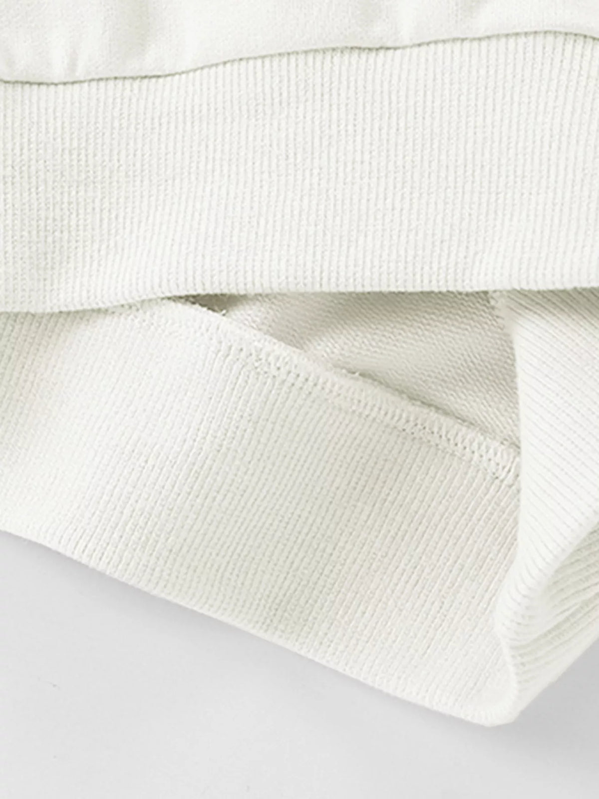 Close-up of the white sweatshirt's ribbed hem.