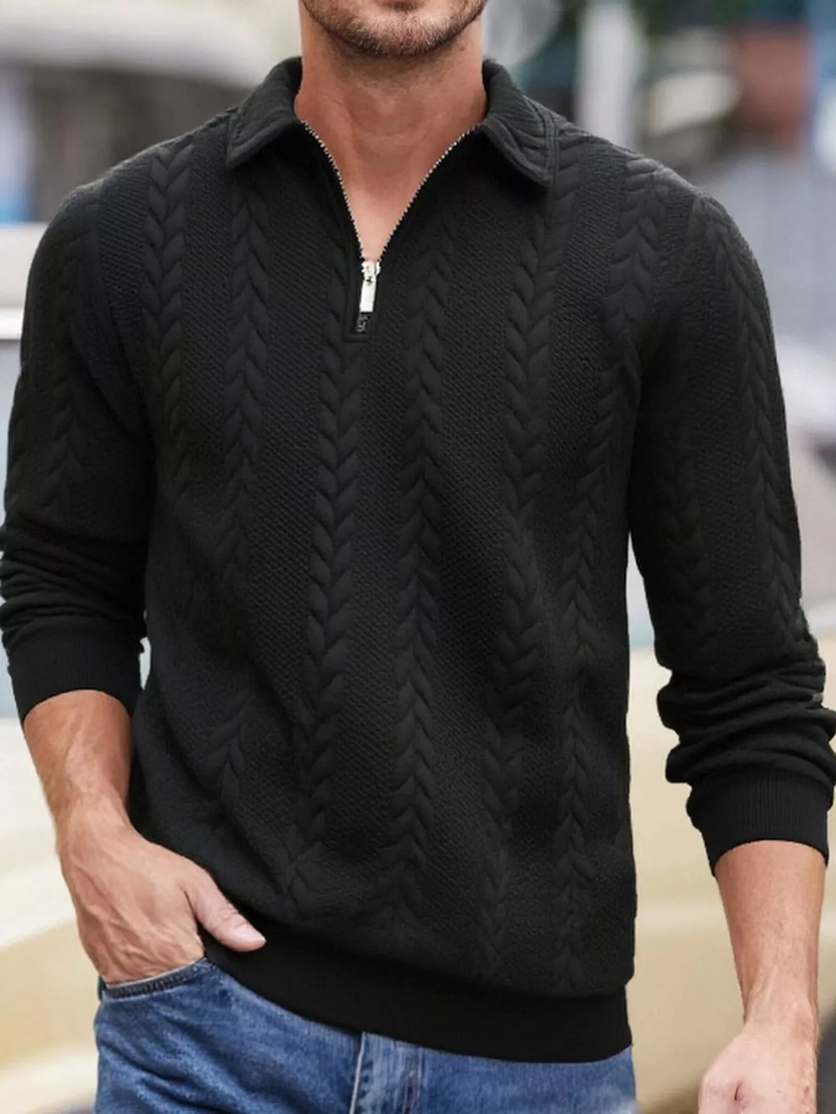 Men's black cable-textured quarter-zip pullover with pointed collar and ribbed cuffs and hem, shown on a model.