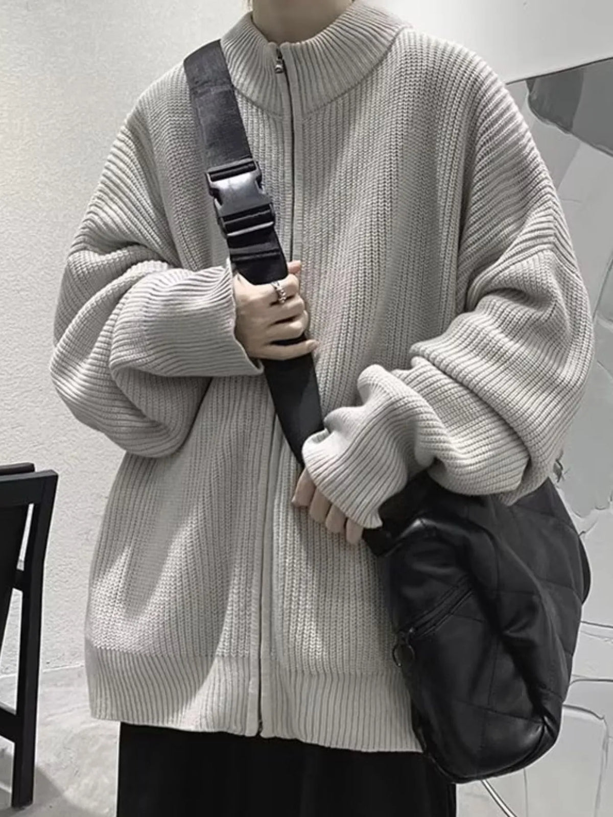 Gray ribbed cardigan zipped up, worn with a separate black crossbody bag and dark trousers.