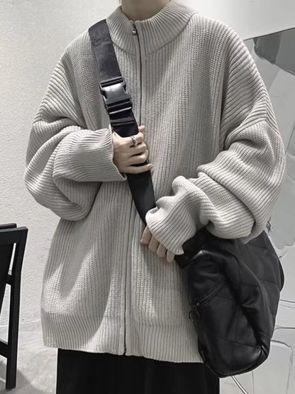 Gray ribbed cardigan zipped up, worn with a separate black crossbody bag and dark trousers.