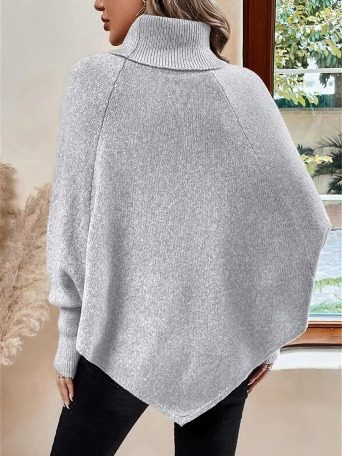 Light gray cable-knit turtleneck cape sweater. Rear view showing cape back and shoulder buttons. Styling accessories are not included.